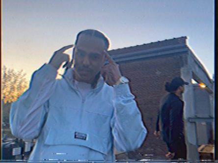 Still from the Lifetime video: a man in a white jacket outside a brick building